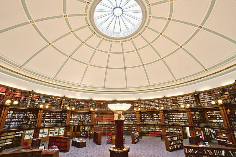 A quiet circular reading room with wooden shelves under a domed skylight.