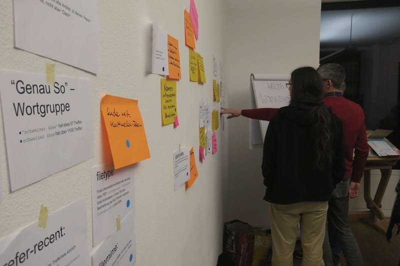 Workshop participants pin and read handwritten notes sorted on a wall.